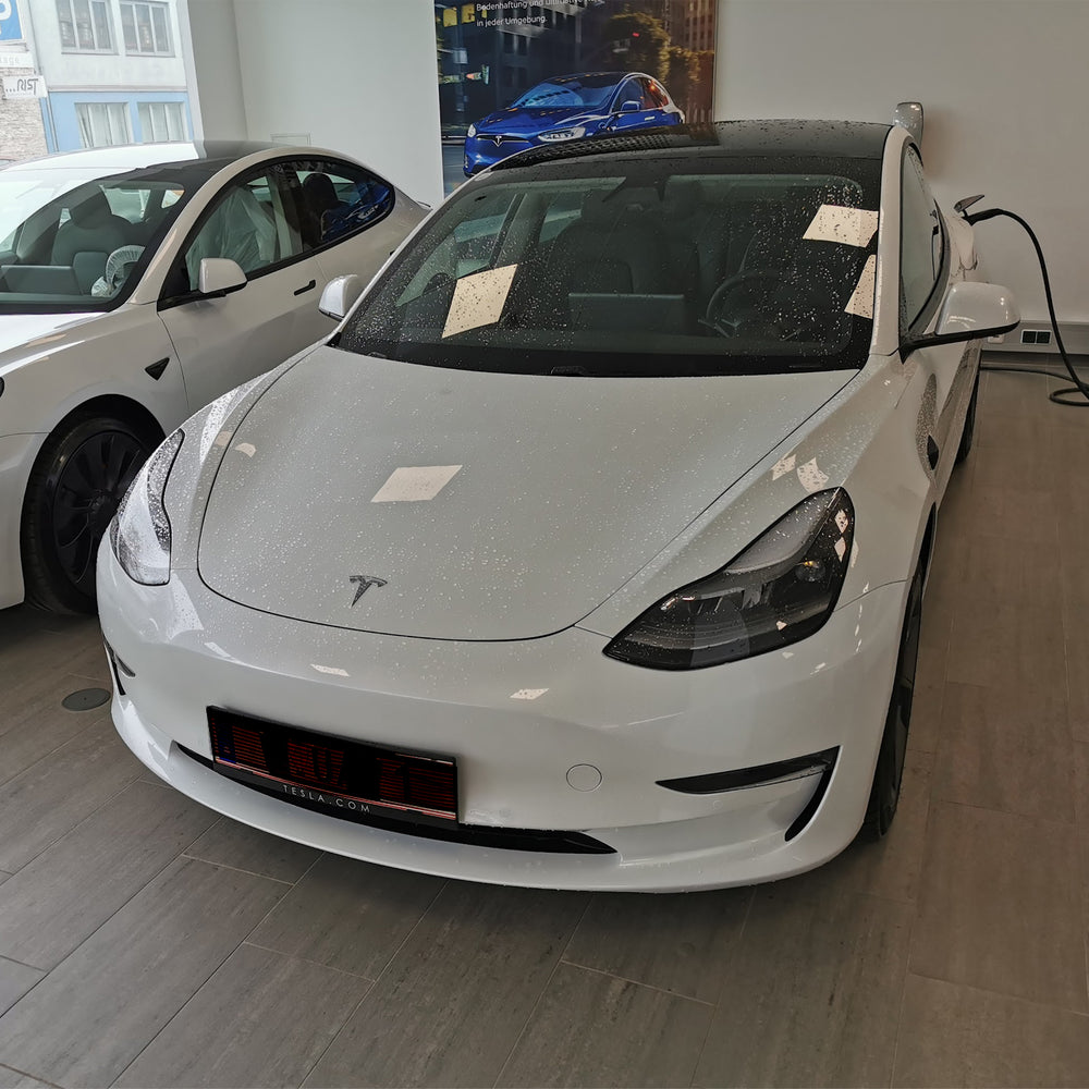 Hvid Tesla Model 3 ved overdragelsen i showroomet