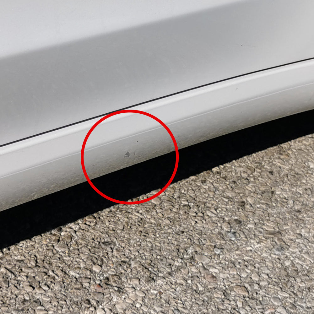 Lakskade markeret med rødt på sidepanelet af en hvid Tesla Model 3