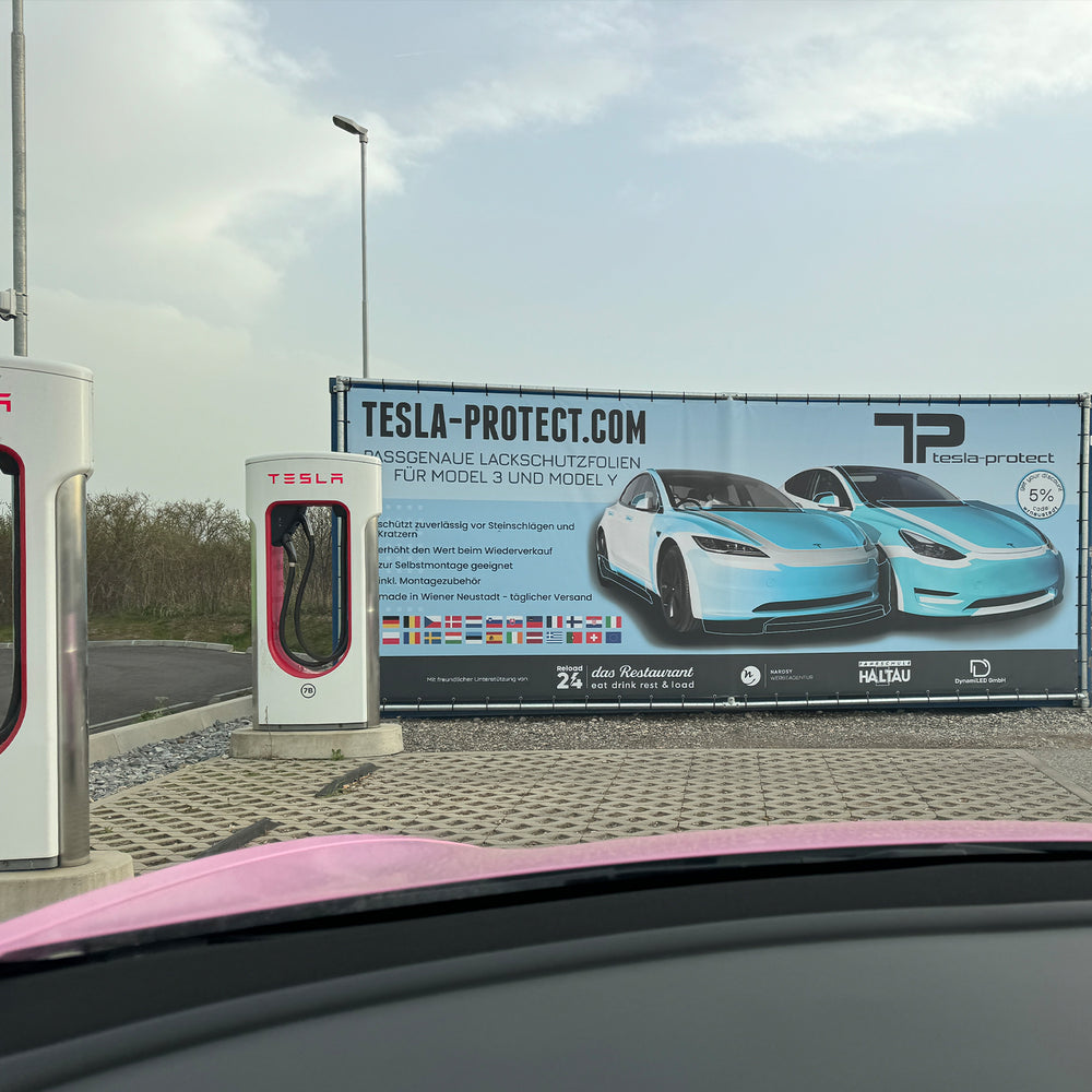Reklamebanner fra Tesla-Protect ved siden af Tesla Superchargere